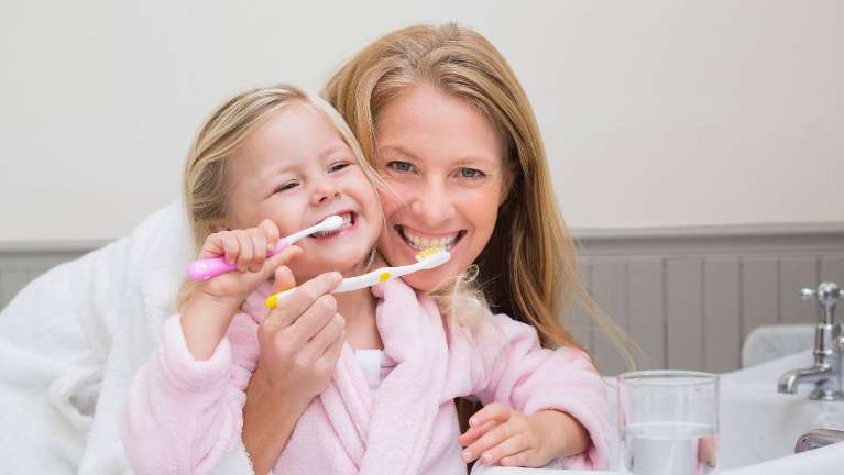 Both are holding toothbrushes and are engaged in the act of brushing their teeth