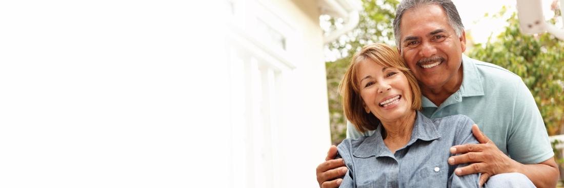 older man and woman smiling after getting dentures